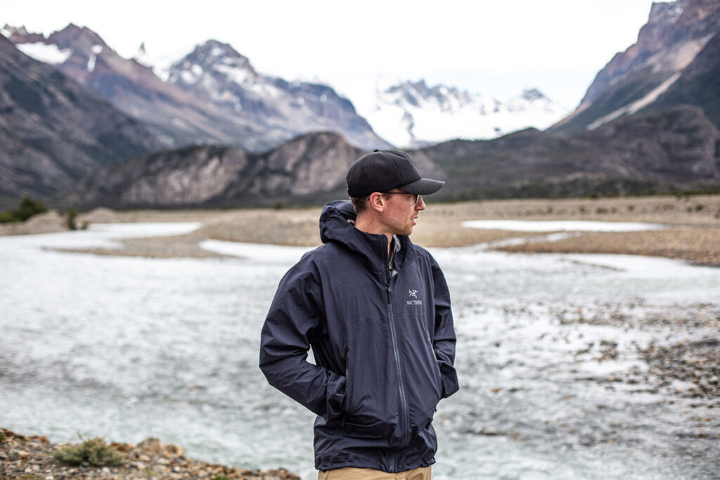 a person wearing Arcteryx jacket in black color standing in mountains