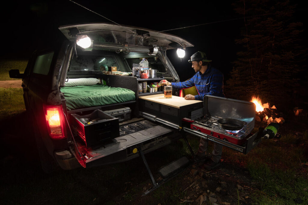 truck bed at night lights setup on the top corners of vehicle a boy cooking